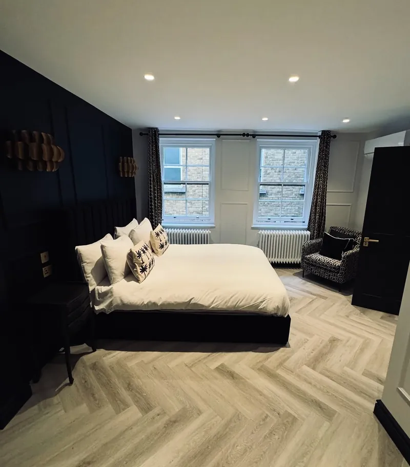 Furnished bedroom in a renovated Mayfair flat with a dark panelled feature wall